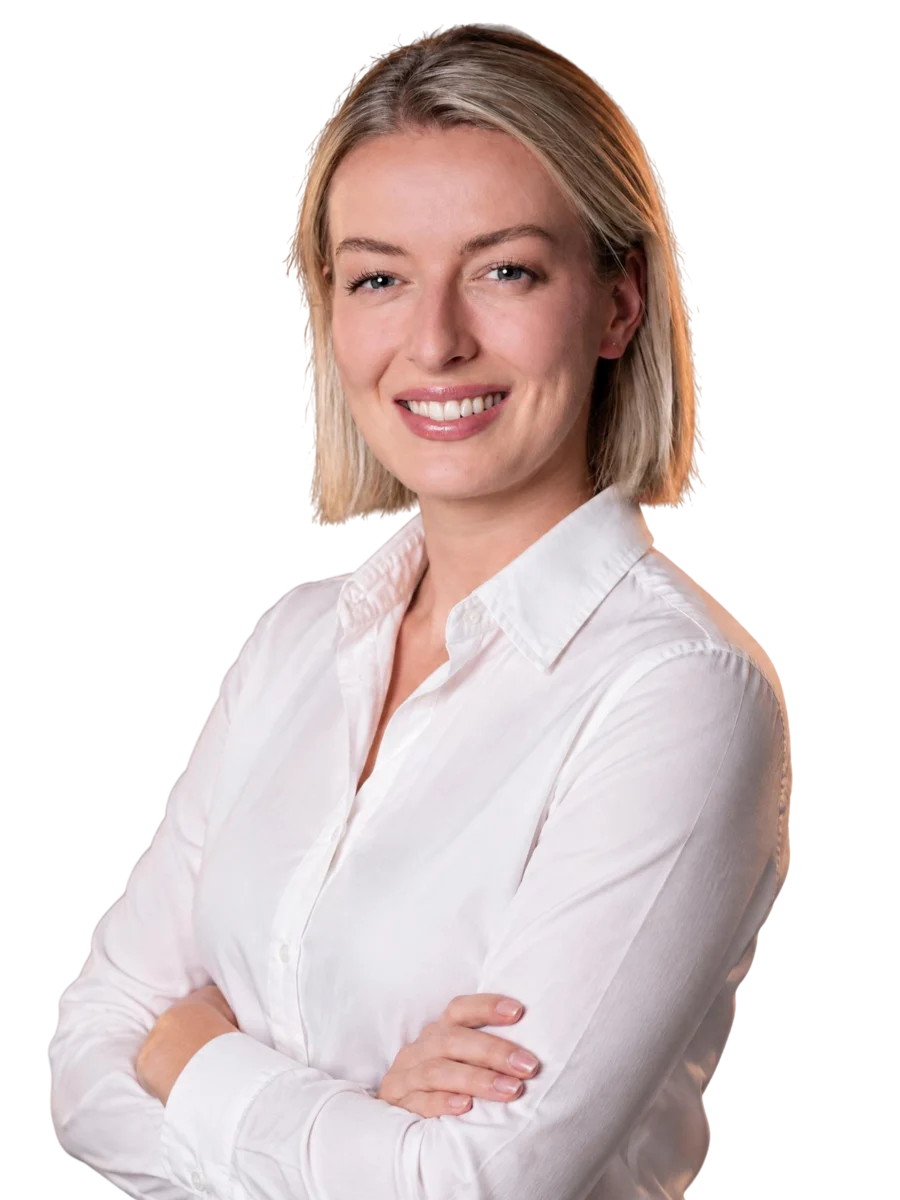 Alexandra Jackowski in weißer Bluse, langes blondes Haar, mit verschränkten Armen lächelnd in die Kamera